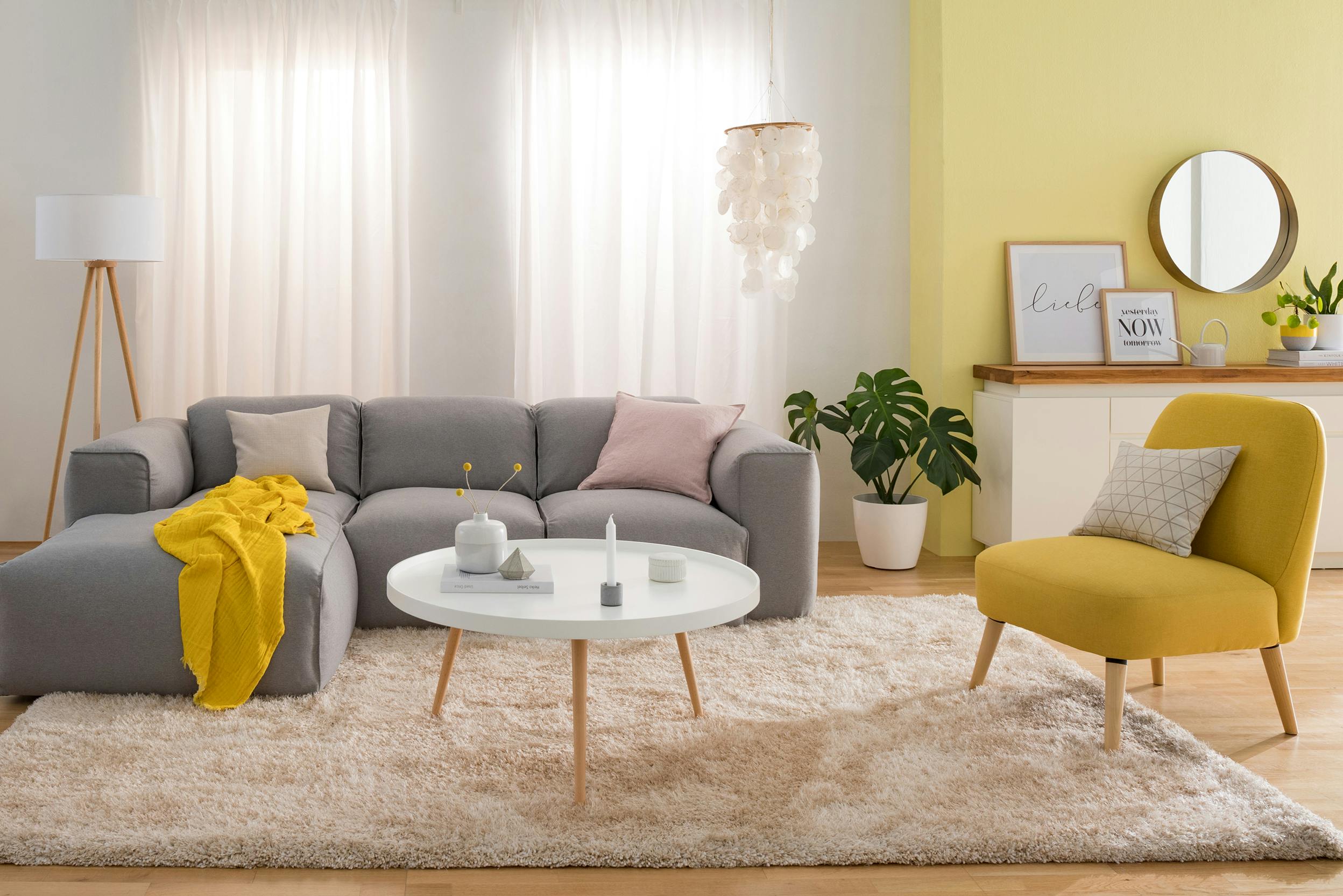 Graues Sofa und gelber Sessel in Wohnzimmer mit gelber Wandfarbe