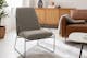 Grauer Sessel mit Metallgestell auf grauem Teppich, dazu ein braunes Ledersofa und ein Sideboard mit Wiener Geflecht.