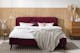 Chambre de style scandinave avec lit capitonné rouge carmin, meubles en bois et lampe en verre