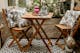Terrasse mit kleinem Gartentisch-Set aus Massivholz, Outdoor-Teppich in Schwarz u. Weiß, Kissen und Deko-Objekten (Butlers).