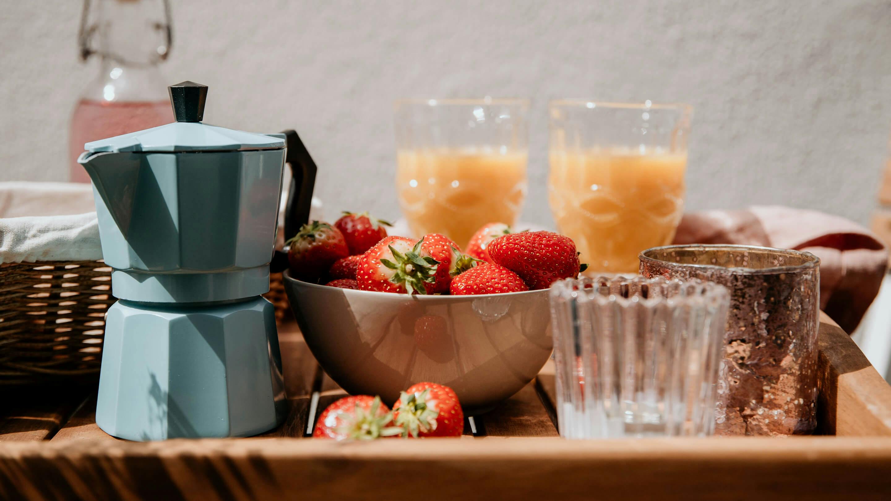 Tablett aus Massivholz mit Kaffeebereiter in Hellblau, Schale mit Erdbeeren, Trinkgläsern mit Saft (Marke: Butlers).