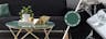 Aufsehenerregende Oberflächenstruktur einer Tischplatte aus grünem Marmor, dekoriert mit goldenen Objekten und einer Grünpflanze; daneben Aufsicht auf eine schwarze Tischplatte in Marmoroptik