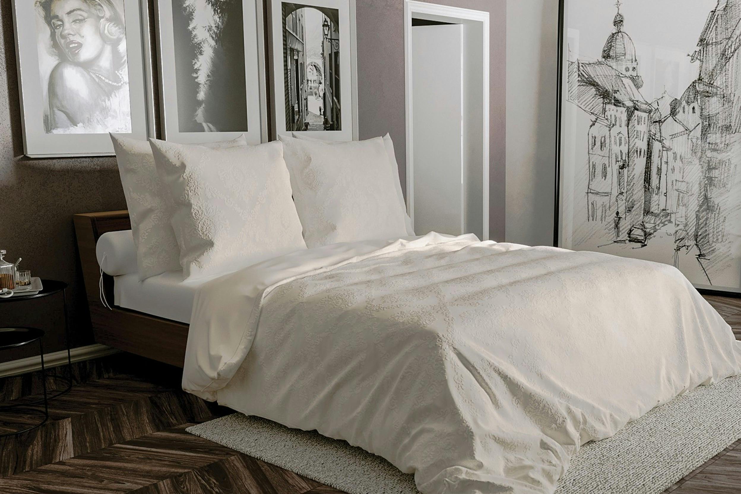 Cremefarbene Bettwäsche mit Brokatmuster in einem Zimmer mit vielen schwarz-weißen Kunstwerken