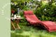 Bain de soleil en bois avec coussin rouge (alternative avec coussin de tête blanc) dans un jardin enchanteur