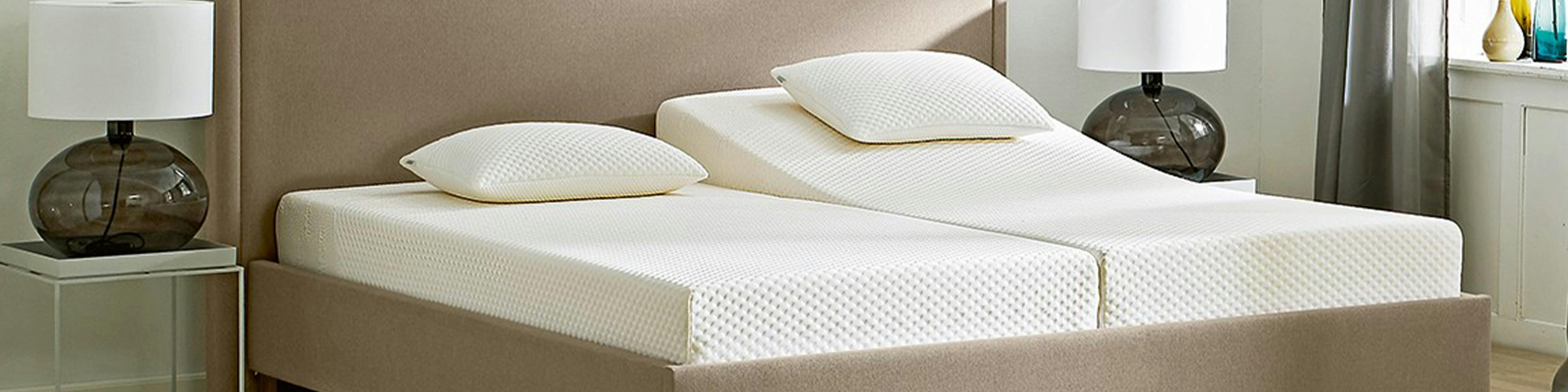 Un grand lit avec deux matelas simples distincts, dont un est surélevé
