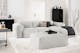 Canapé 3 places Hudson recouvert du populaire tissu Saia, dans un salon à l'aménagement minimaliste avec tapis en laine, table basse noire et photographies encadrées.