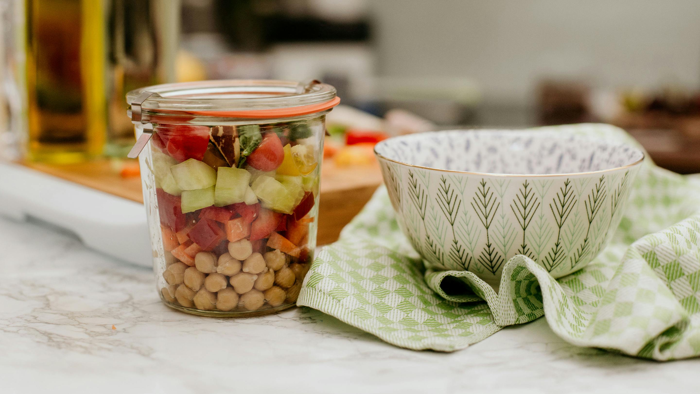 Schüssel mit feinem Muster und Glasbehälter mit Kicherebsen und frisch geschnittenem Gemüse (Marke: Butlers).