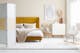 Schlafzimmer im Skandi-Stil mit senfgelbem Polsterbett aus Samt mit Chesterfield-Knöpfung und vielen flauschigen Textilien