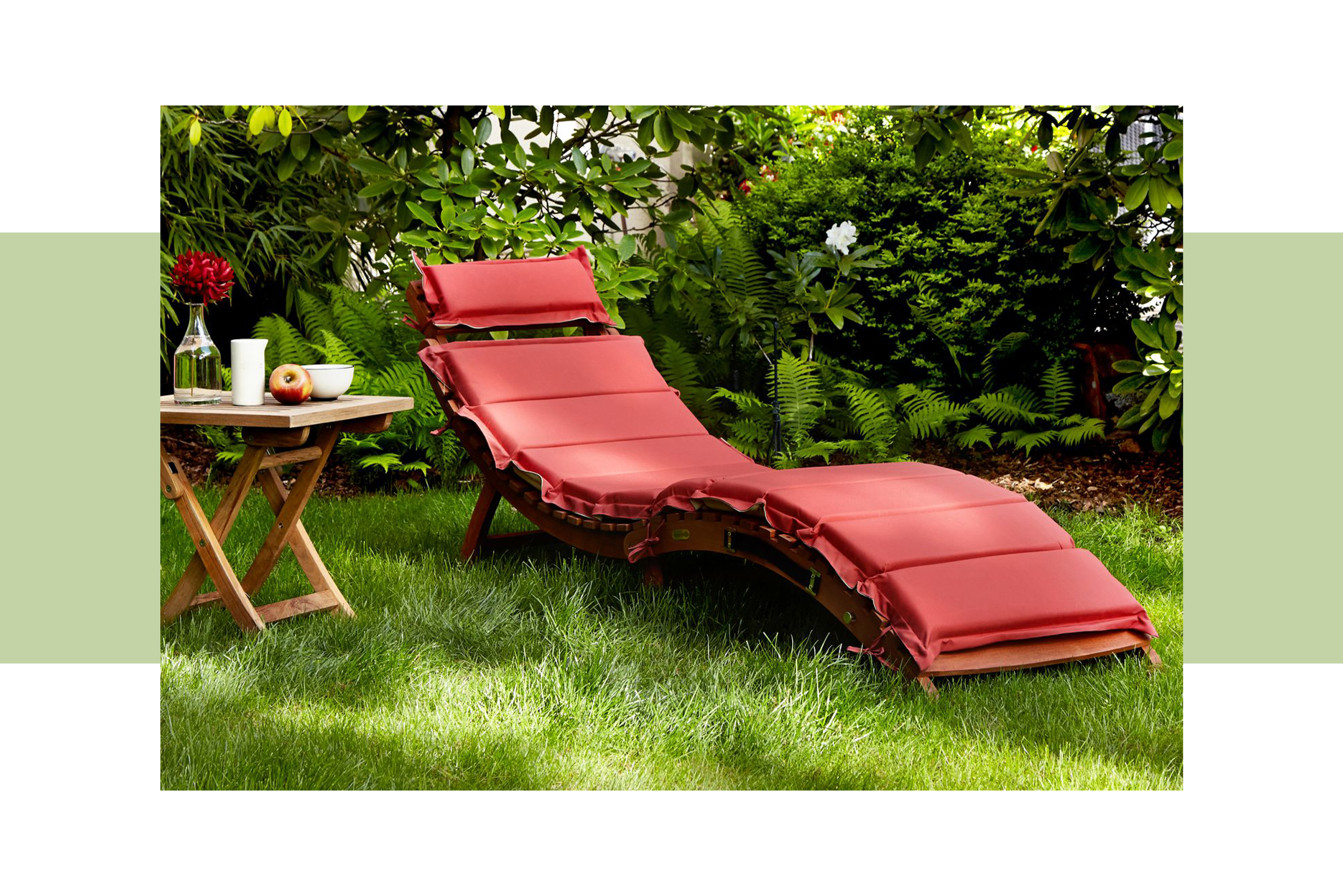 Gartenliege aus Holz mit roter Auflage (alternativ mit weißen Kopfkissen) im grünen Garten