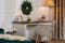 Gästezimmer mit Büroecke mit einem Schreibtisch aus weißem und dunklem Holz, einem Armlehnenstuhl mit kariertem Muster, einer Stehlampe mit Rattanschirm, Samtvorhängen und Weihnachtsdeko.