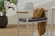 Scandinavische zitbank van licht massief hout met grijs zitoppervlak en dekentje met patroon.