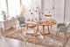 Table de salle à manger Voksa, de la marque exclusive home24 Ars Natura, recouverte de vaisselle BUTLERS gris clair et blanche et de décorations de Pâques colorées, et des chaises de salle à manger assorties en gris de style scandinave, un buffet blanc et un tapis beige.