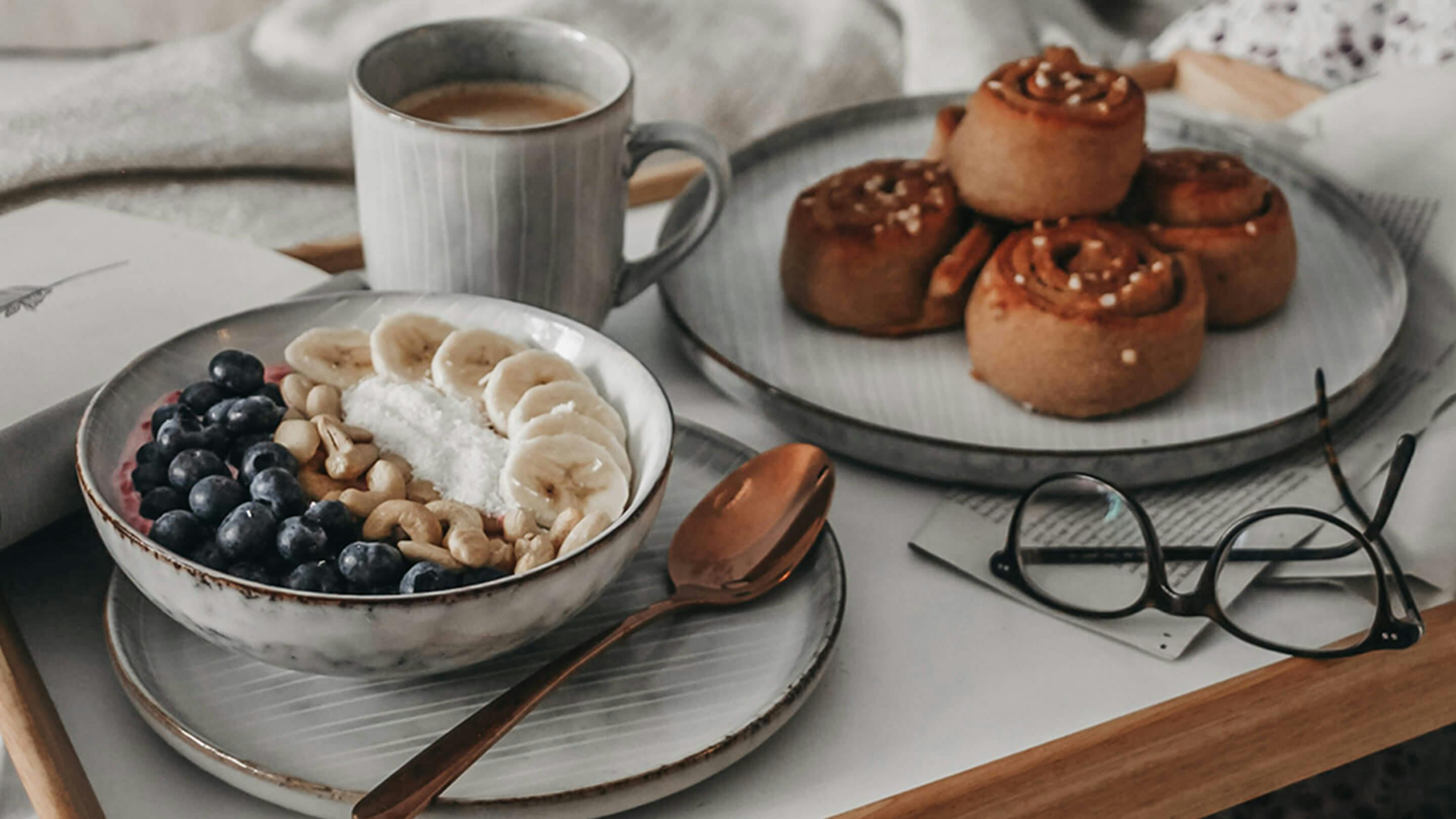Frühstücksset in Grau (Butlers) auf Tablett: kleiner Teller, Schale mit Müsli, grosser Teller mit Zimtschnecken, Kaffeebecher.