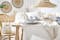 Lässiges Tisch-Setting inspiriert von Ferienhäusern Australiens mit Fokus auf Blau, Cremefarben und Naturmaterialien, daher mit blauem Geschirr, Leinentischdecke und Bast-Tischsets eingedeckt sowie mit Kissen und Wandgirlande im Boho-Stil dekoriert