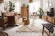 Wohnzimmer im Boho-Style mit einem Ledersofa, Holzmöbeln mit Wiener Geflecht, Rattan, vielen Pflanzen, Textilien und Deko aus Messing