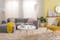 Helles Wohnzimmer mit hellgrauem Sofa, weißem Couchtisch und einer Stehlampe im Skandi-Stil, einem gelben Skandi-Sessel, einer Pendelleuchte aus Muscheln, einem weißen Sideboard und schönen Textilien.