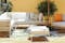 Modulaire loungemeubels voor terras, tuin en balkon van teakhout met een frame van roestvrij staal en lichtgrijze bekleding, gecombineerd met een ootdoor-vloerkleed en kussens.
