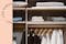 Intérieur d'une armoire organisée à la perfection avec certains vêtements suspendus, d'autres pliés sur des étagères.