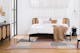 Slaapkamer in mid century modern met een bed, dressoir en fauteuil in donker hout en Weens vlechtwerk. Plus wit beddengoed, beige textiel, een zwarte hanglamp, vazen met pampagras, een vloerkleed met patroon in gedempte kleuren en een zwart nachtkastje.