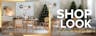 Salle à manger avec des meubles de Studio Copenhagen : une table en bois clair, des chaises cannées, un buffet blanc, un fauteuil gris et des suspensions en verre, un sapin de Noël décoré, une déco de table festive, de la vaisselle noire, des vases noirs et blancs avec de l'herbe de la pampa et autres objets décoratifs en noir et blanc.