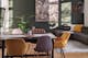 Table de salle à manger en bois foncé et métal noir, chaises en rotin et colorées, suspension industrielle avec simples ampoules et câbles apparents, canapé d'angle gris et lampadaire arc en arrière plan.