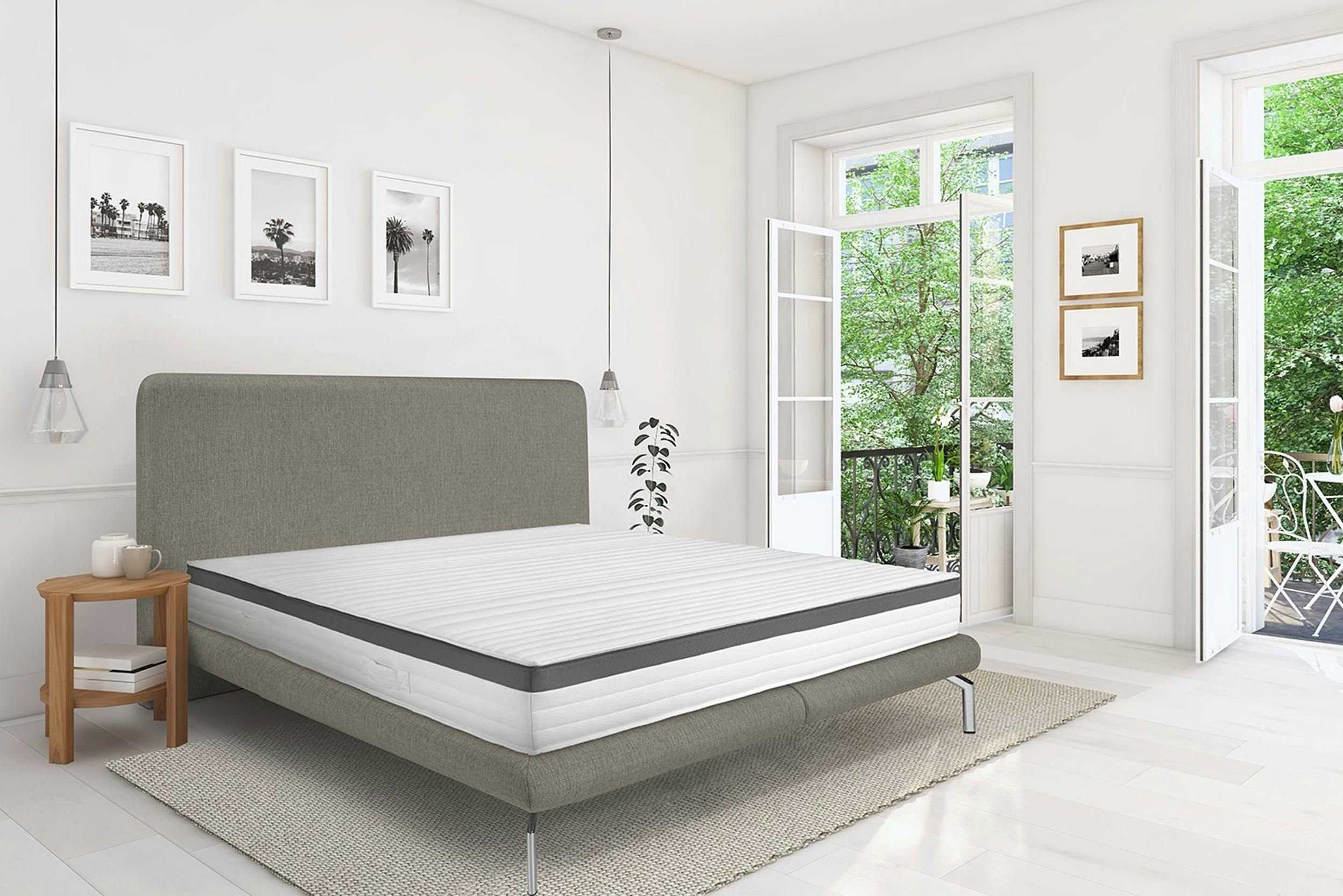 Helles Zimmer mit weit geöffneten Fenstern und grauem Bett samt Matratze