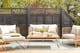Modulaire loungemeubels uit de serie Teakline Exklusiv voor terras, tuin en balkon, gemaakt van teakhout met een frame van roestvrij staal en lichtgrijze bekleding, gecombineerd met een ootdoor-vloerkleed en kussens.