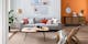 Salon composé d'un canapé gris clair agrémenté de coussins colorés et de meubles en bois et rotin