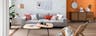 Salon composé d'un canapé gris clair agrémenté de coussins colorés et de meubles en bois et rotin