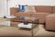 Salon avec canapé d'angle couleur terre accessoirisé de coussins, table en verre et objets déco.