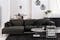 Dunkelgraues Ecksofa Gaillon by Studio Copenhagen im elegant-schlichten Design mit gleichfarbigen Kissen, kombiniert zu einem runden Couchtisch mit weißer Marmor-Tischplatte und schwarzem Hochflorteppich.