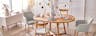 Esstisch Voksa der home24 Exklusivmarke Ars Natura, eingedeckt mit hellgrauem und weißem BUTLERS-Geschirr und bunter Osterdeko. Dazu passende Esszimmerstühle in Grau im Skandi-Stil, ein weißes Sideboard und ein beiger Teppich.