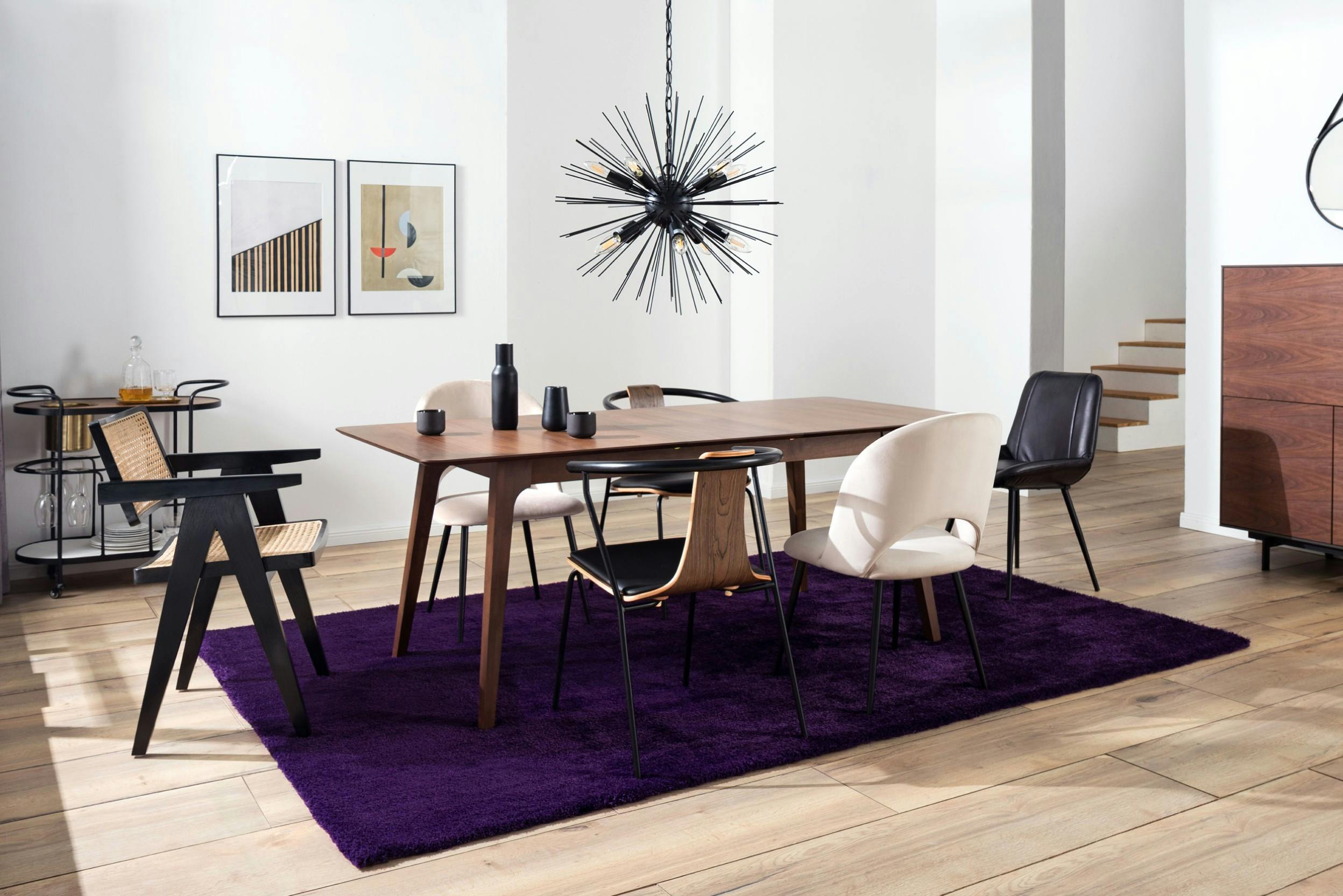 Essbereich mit Tisch, Polster-, Leder- und Holzstühlen, lila Teppich und schwarzer Pendelleuchte