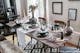 Salle à manger en bois sombre rustique avec banc, chaises à entretoise, table dressée, vaisselier avec vitrine .