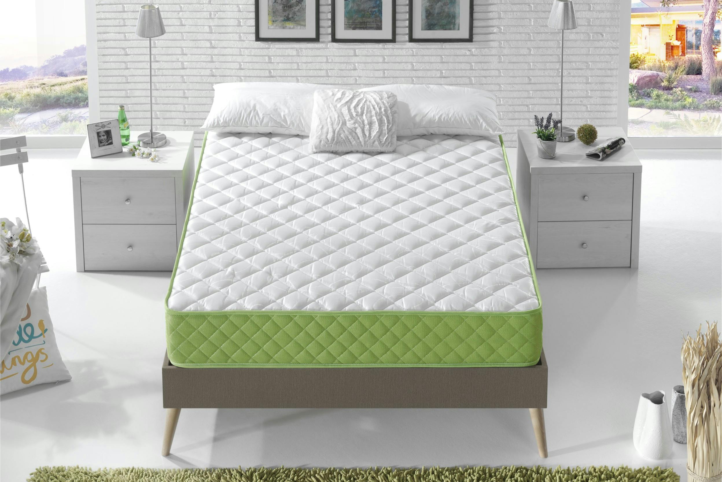Schlafzimmer mit weißen Möbeln und grauem Polsterbett mit weiß-grüner Gelmatratze