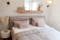 Bett und Bettwäsche in Altrosa kombiniert mit Pampasgras, Wandleuchten und einem rahmenlosen Spiegel