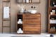 Salle de bain avec des meubles en bois de sheesham massif de la série exclusive Trangle de home24, des accessoires façon spa à domicile comme des serviettes enroulées, des produits de soin et une décoration naturelle.