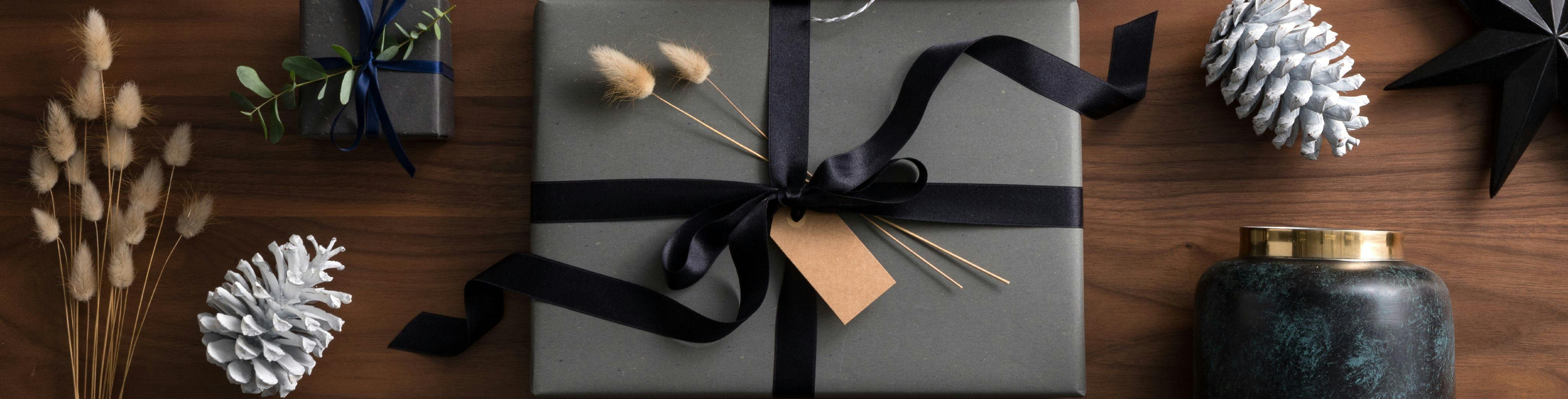 photo de cadeau au papier emballage gris avec plantes artificielles et ruban noir