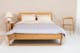 Schlafzimmer mit Holzbett inklusive Bettdecke und Kissen, Stuhl und Nachttisch