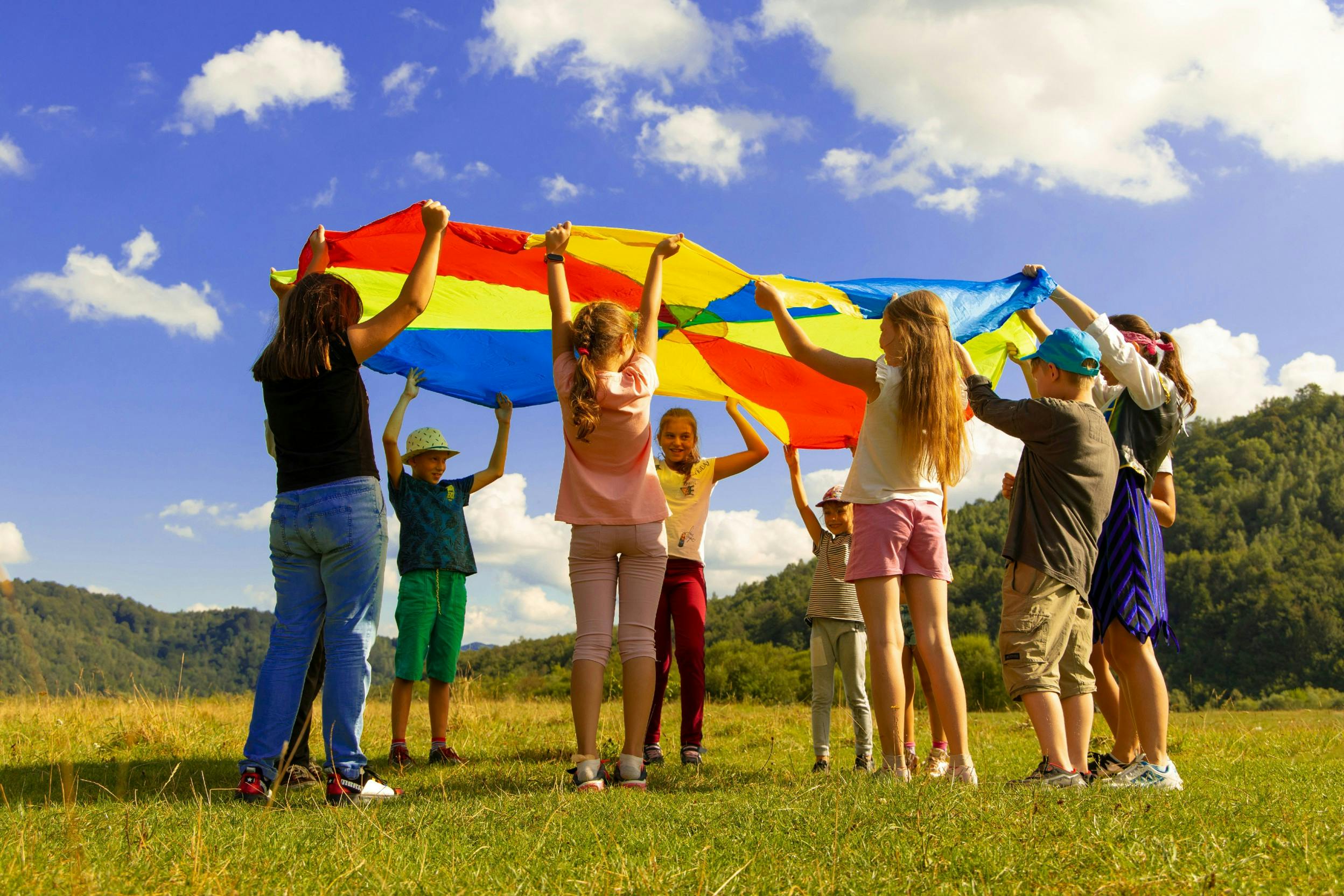 Kindergruppe beim Spielen mit einem Schwungtuch auf einer Wiese