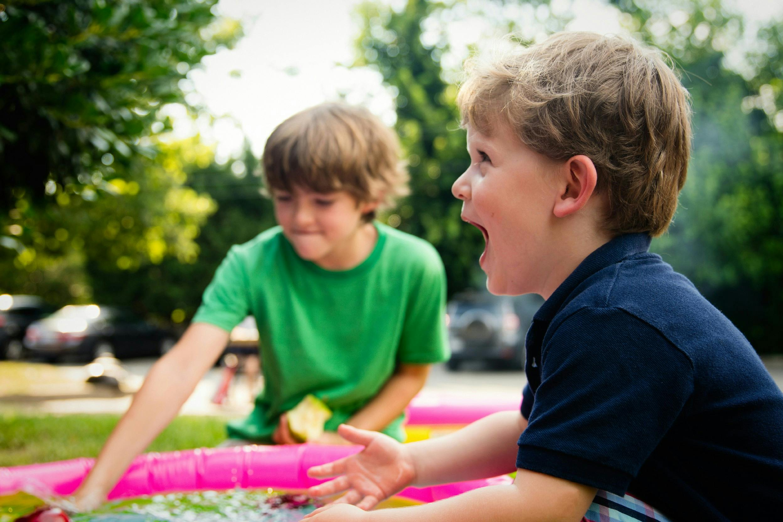 Zwei Jungen angeln Äpfel aus einem aufblasbaren Pool im Garten