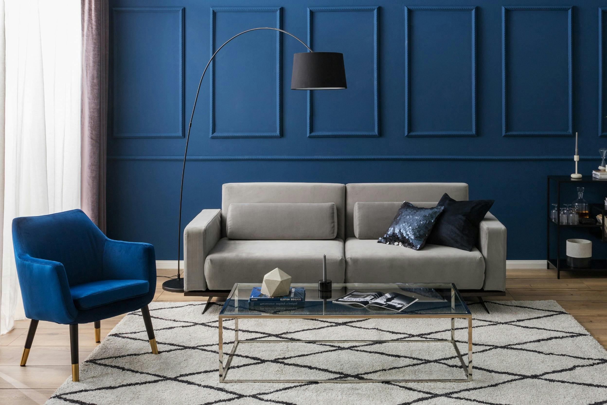 Graues Samtsofa mit blauem Sessel und blauer Wandvertäfelung