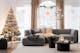 Wohnzimmer mit hellgrauem Ecksofa Alon der home24 Exklusivmarke Studio Copenhagen auf einem beigen Teppich, dazu ein runder, schwarzer Couchtisch, ein dunkelgrauer Pouf, Textilien, Pendelleuchten aus Glas, ein geschmückter Weihnachtsbaum, Leuchtsterne sowie Weihnachtsdeko.