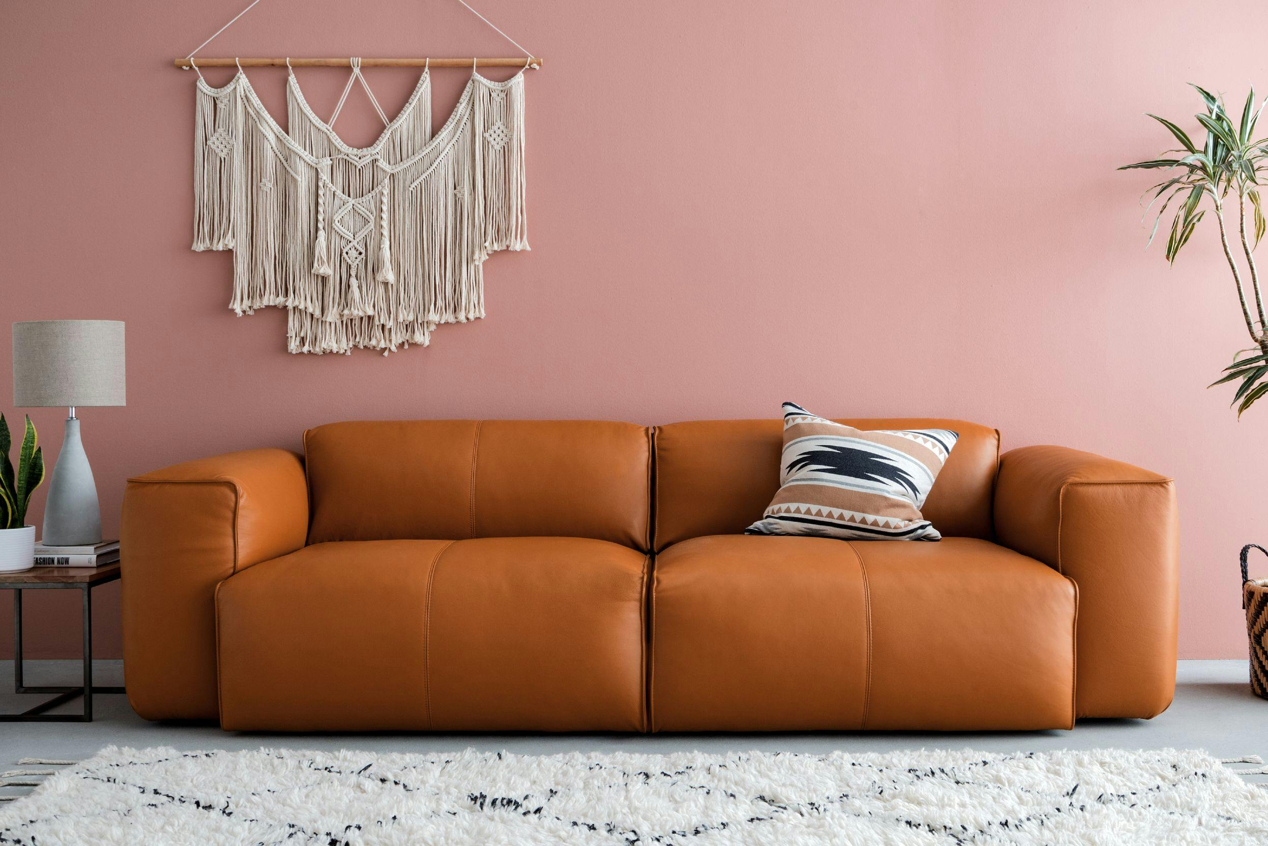Un salon avec un canapé en cuir couleur cognac, un tapis beige et des éléments décoratifs