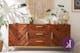 Musthave-dressoir Loga van kollected van acaciahout met voorkant met visgraatmotief en goudkleurige meubelpoten en handgrepen.