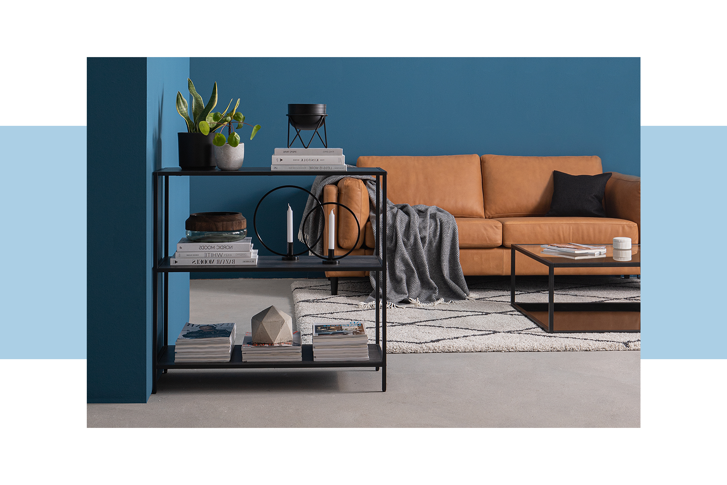 Offenes, schwarzes Regal als dekorativer Raumteiler im Wohnzimmer sowie als Badregal, in dem sich eine graue Katze versteckt hat