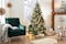 Petrolkleurige fluwelen fauteuil met lichtgrijze bekleding, daarnaast een feestelijk versierde kerstboom met veel cadeautjes en kerstversiering (voornamelijk in zilver, goud en lichtblauw).