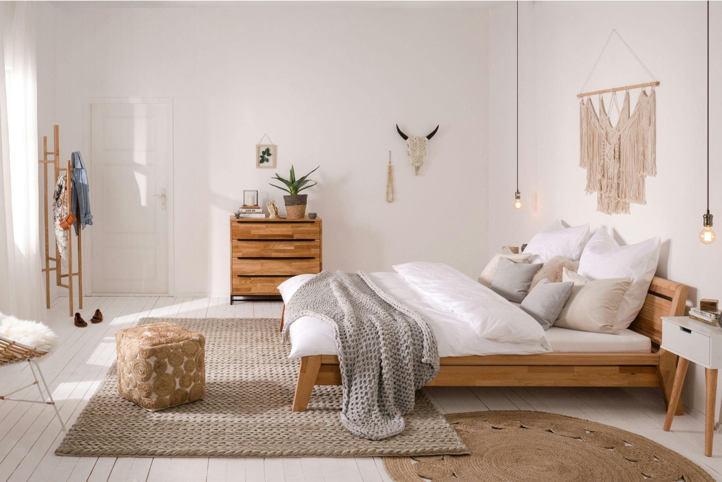 Harmonieuze woonkamer met natuurlijke kleuren, houten bed, kast, vloerkleden, wit beddengoed