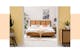 Chambre de style bohème avec mur jaune et meubles cannés, tête de lit cannée ; lit boxspring blanc avec haute tête de lit capitonnée, coussins et attrape-rêves.