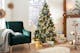 Fauteuil en velours bleu pétrole avec plaid gris clair, cadeaux au pied d'un sapin de Noël avec décorations principalement dans les tons argentés, dorés et bleus clairs